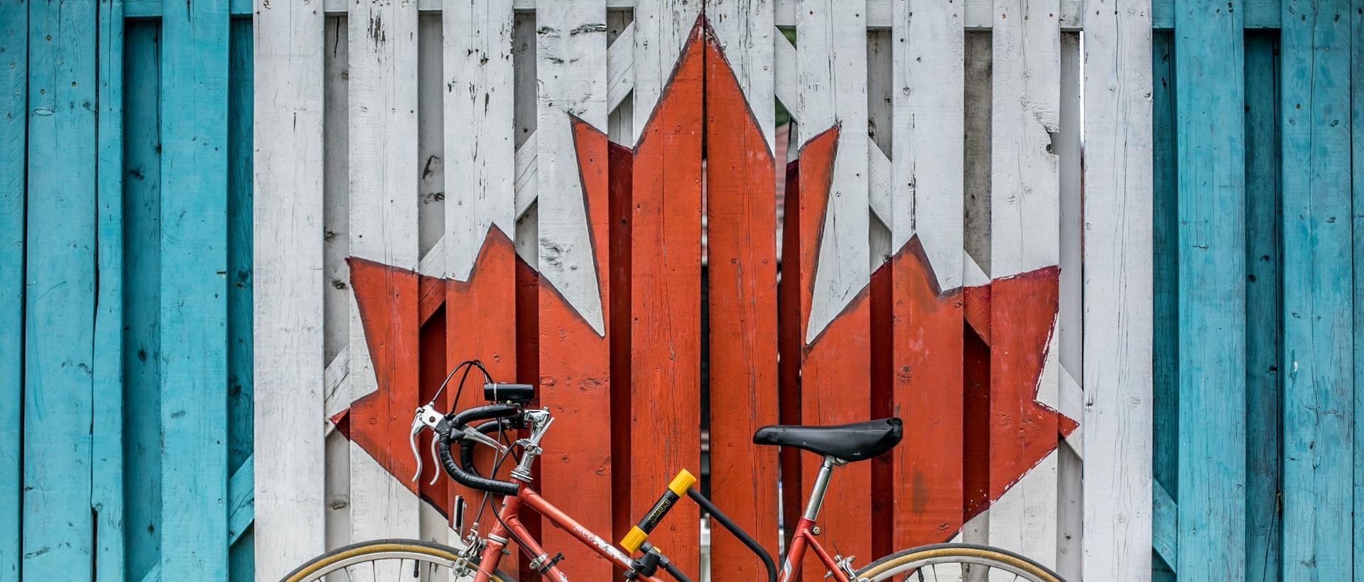 red road bike beside red and white wooden maple leaf painted wall